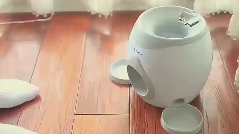 Dog dropping tennis ball into treat dispenser